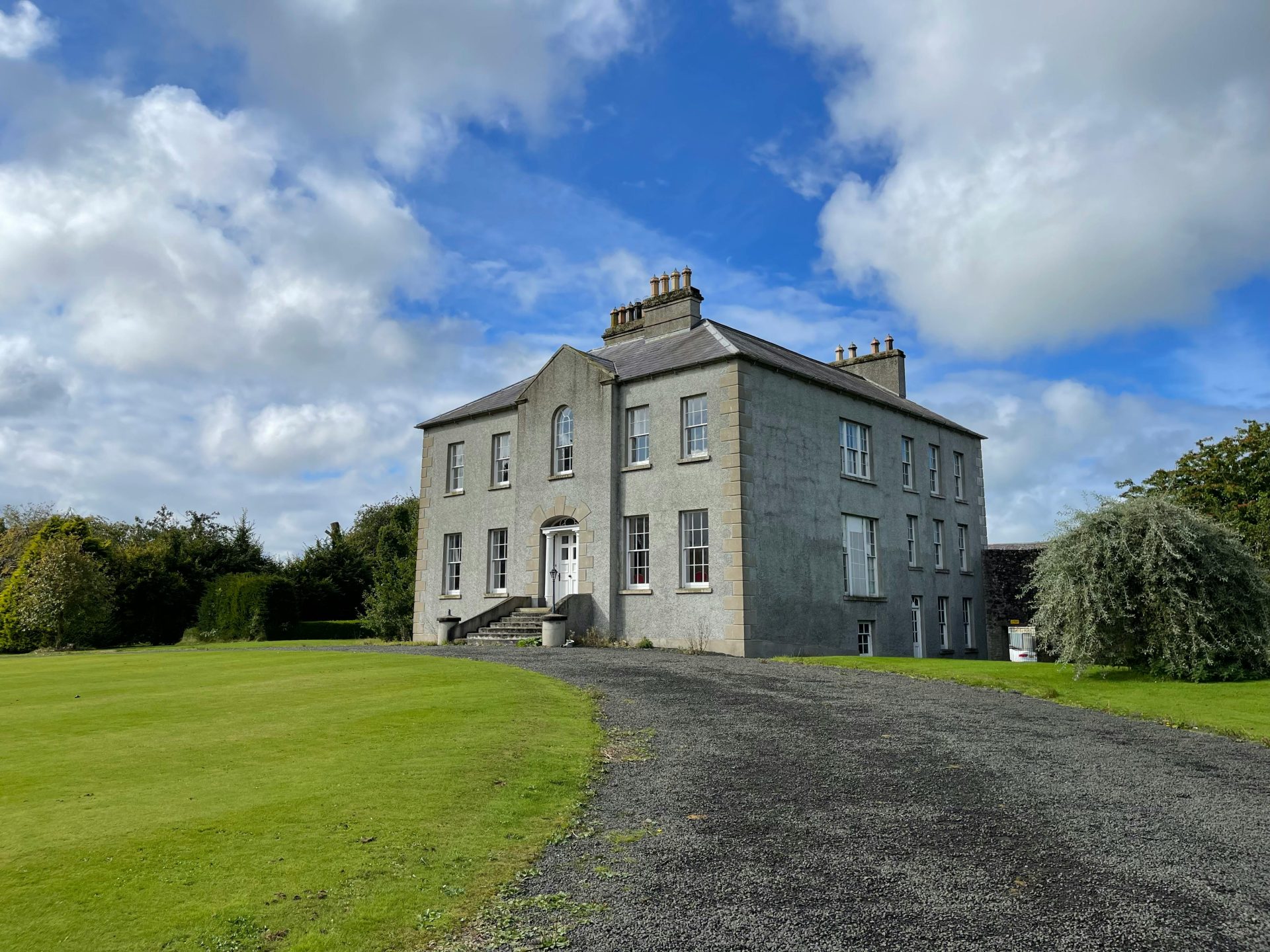 Historic countryside house in Ballymoney, Northern Ireland, amid lush green gardens.